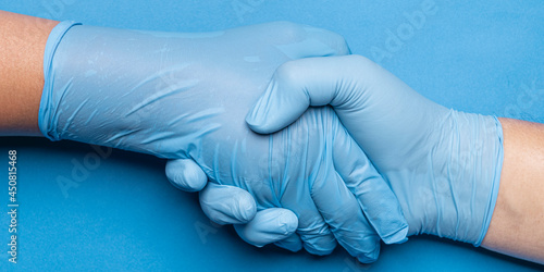 hand of doctor in blue latex glove and patient shaking hands.