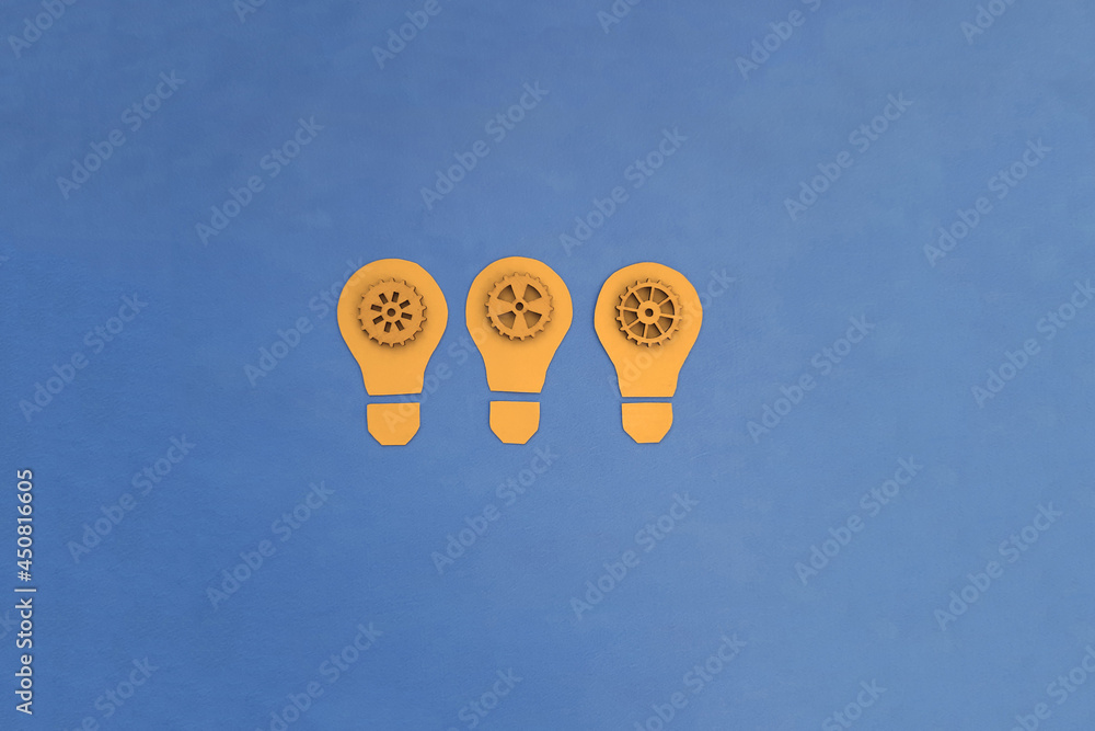 Electric light bulbs are yellow, inside there are wooden gears of blue color on a blue background. Ideas, creativity.