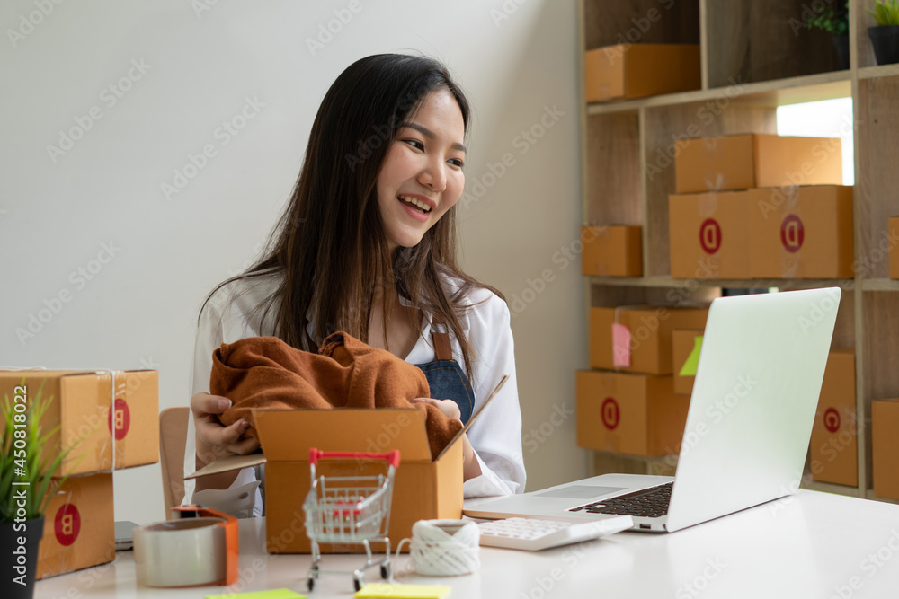 Startup small business entrepreneur SME, young asian woman working with laptop computer and delivery packaging box, online market packing, SME e-commerce seller concept. Startup small business entrepreneur SME, young asian woman working with laptop computer and delivery packaging box, online market packing, SME e-commerce seller concept.