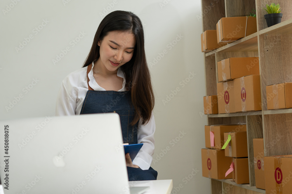 Startup small business entrepreneur SME, young asian woman working with laptop computer and delivery packaging box, online market packing, SME e-commerce seller concept. Startup small business entrepreneur SME, young asian woman working with laptop computer and delivery packaging box, online market packing, SME e-commerce seller concept.