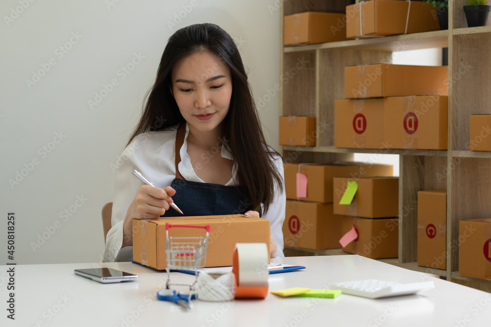Startup small business entrepreneur SME, young asian woman working with laptop computer and delivery packaging box, online market packing, SME e-commerce seller concept. Startup small business entrepreneur SME, young asian woman working with laptop computer and delivery packaging box, online market packing, SME e-commerce seller concept.