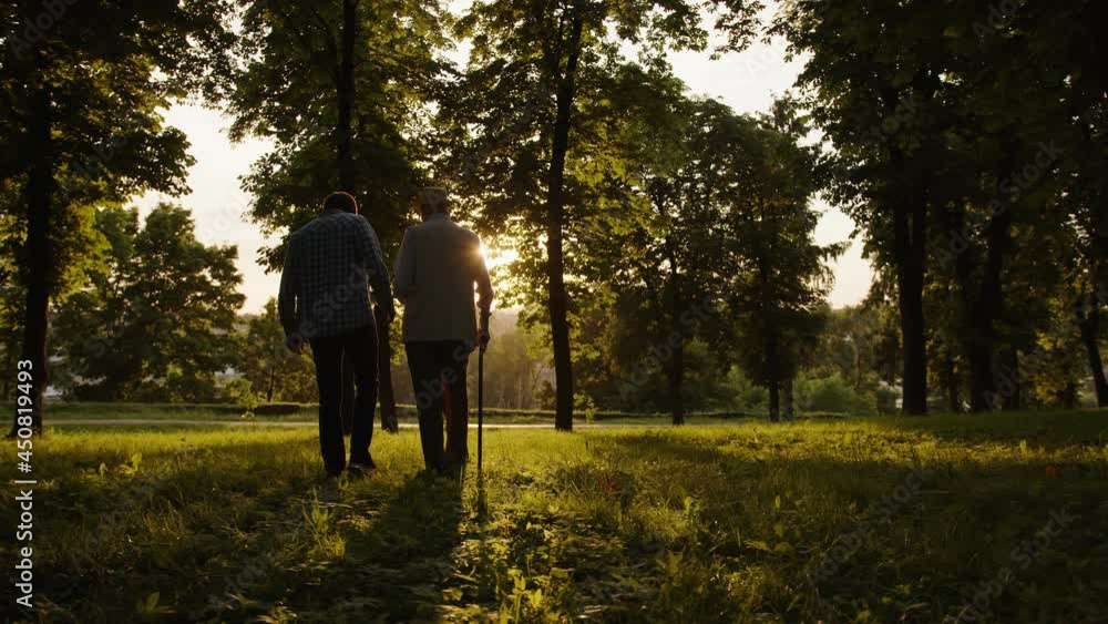 A loving grandson shows his elderly grandfather a beautiful sunset in the park. A loving grandson shows his elderly grandfather a beautiful sunset in the park.