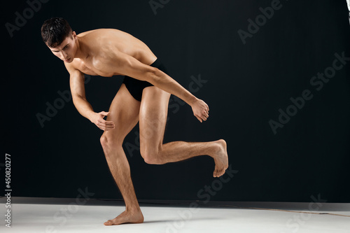 athletic man with pumped up naked body in black panties bent body