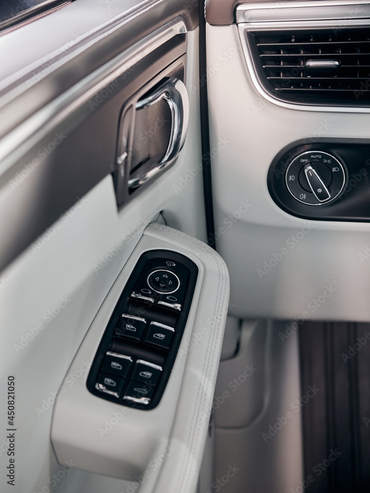 Car white leather interior detail. Windows control buttons and door handle.
