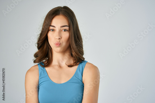 attractive brunette in a blue t-shirt with emotions fashionable hairstyle studio