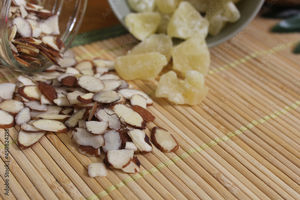 Sliced Almonds and Dried Pineapple on Bamboo Mat Close up Sliced Almonds and Dried Pineapple on Bamboo Mat Close up