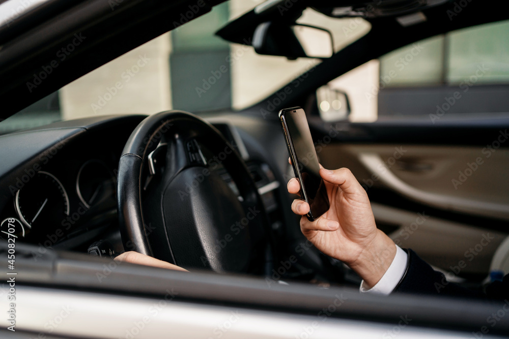 A professional manager in a business suit answers a voice message to clients. The entrepreneur is in the car. The lawyer holds the phone in his hand and calls.