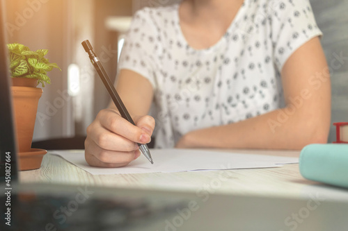 Young woman writing and searching internet on laptop computer. E-learning and online study concept. Management and education background