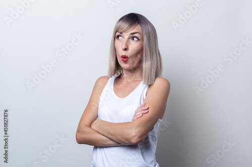 Surprised young woman holding her arms crossed on a light background