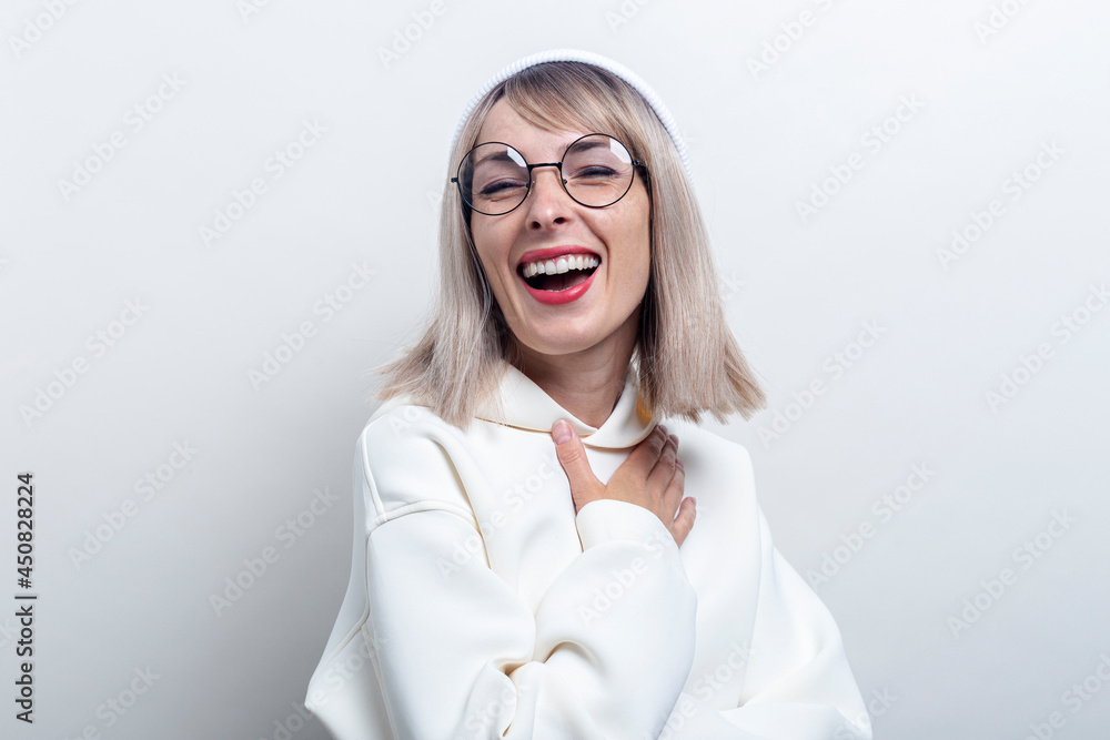 Cheerful young girl in glasses in a hoodie on a light background Cheerful young girl in glasses in a hoodie on a light background