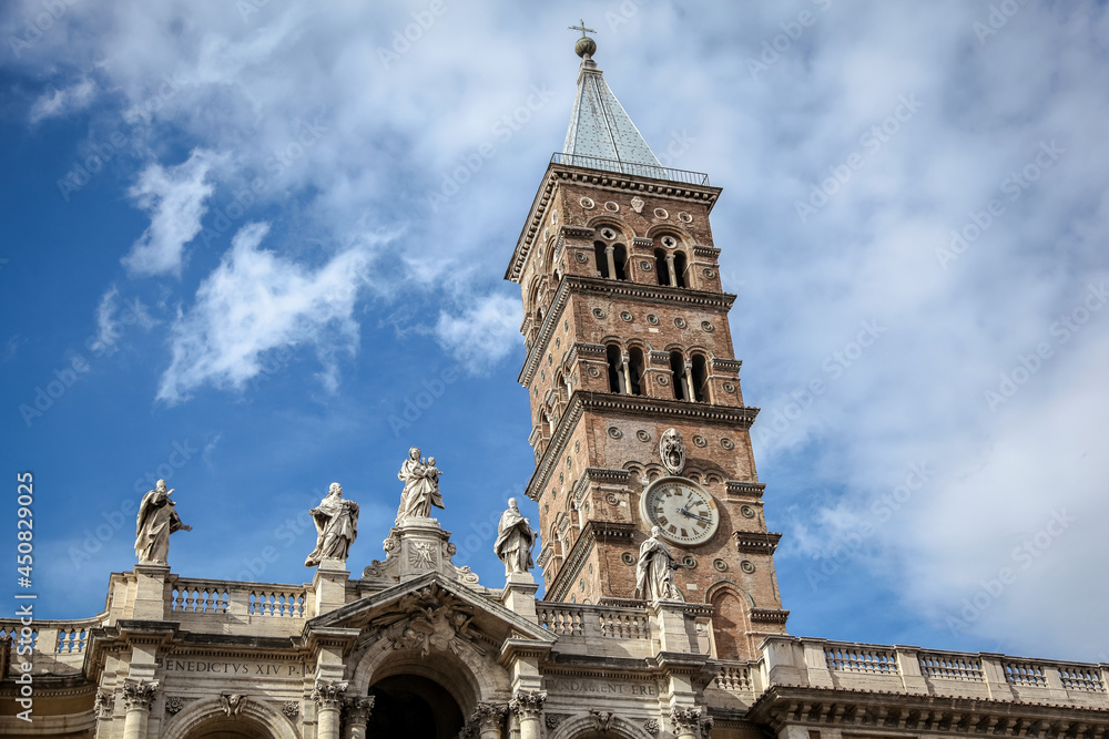 The bell tower of The Basilica of Saint Mary Major (Italian: Basilica di Santa Maria Maggiore) in Rome, against the background of a blue cloudy sky - obrazy, fototapety, plakaty 
