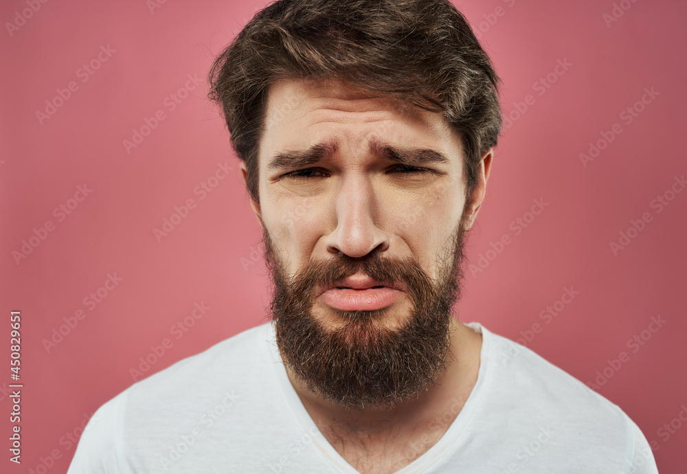Obraz premium bearded man in a white t-shirt hand gestures anger pink background
