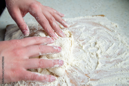 A woman kneads dough on a table with flour