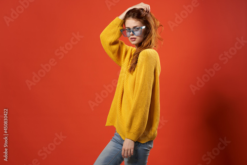 woman in a yellow sweater blue glasses studio fashionable hairstyle red background © SHOTPRIME STUDIO
