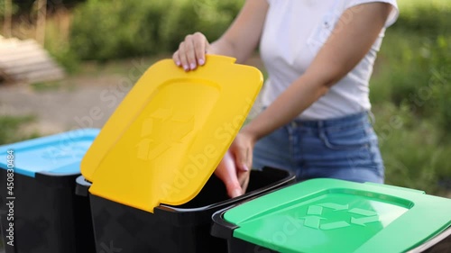 Woman throwing out in recycling bin washed and empty shampoo and deodorant bottles. Female looks at the packages to find out in wich recycling bin throw the garbage