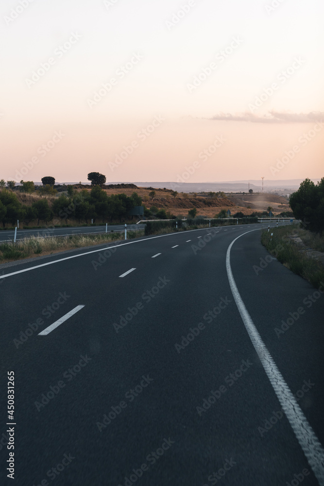 road making a curve in a landscape of a sunset