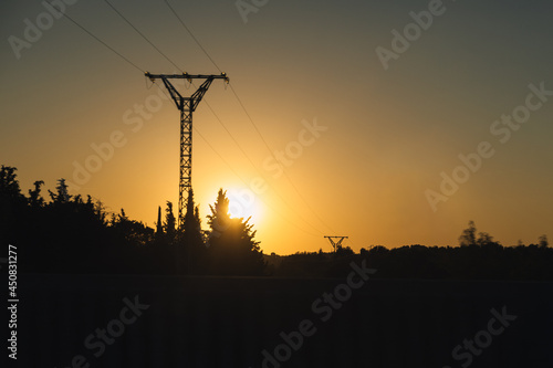 Silhouette of a high voltage electric tower in a sunset with selective focus