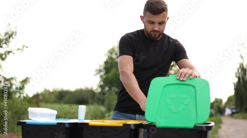 Handsome man put garbage into recycling bins outddors. Concept of recycling. Tree bins, green, yeallow and blue. Lady put different kind of rabbish in trash container photo