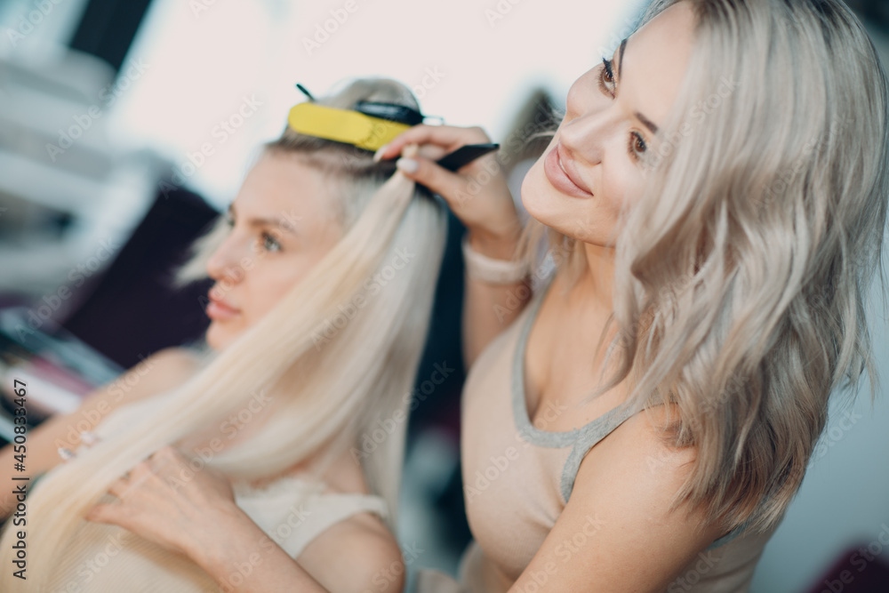 Hairdresser female making hair extensions to young woman with blonde hair  in beauty salon. Professional hair extension try check Stock Photo | Adobe  Stock