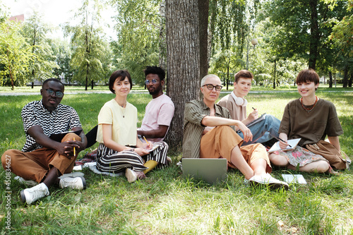 Group of people sitting on the grass and looking at camera they meeting in the park at seminar © AnnaStills