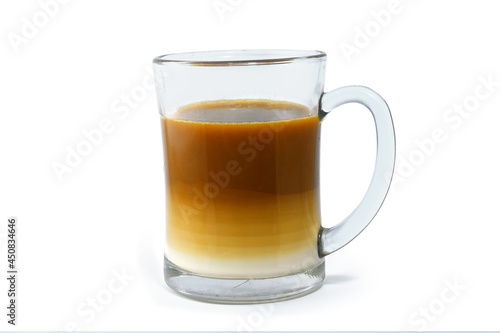 Two layers of milk coffee in a transparent glass, front view, isolated on a white background