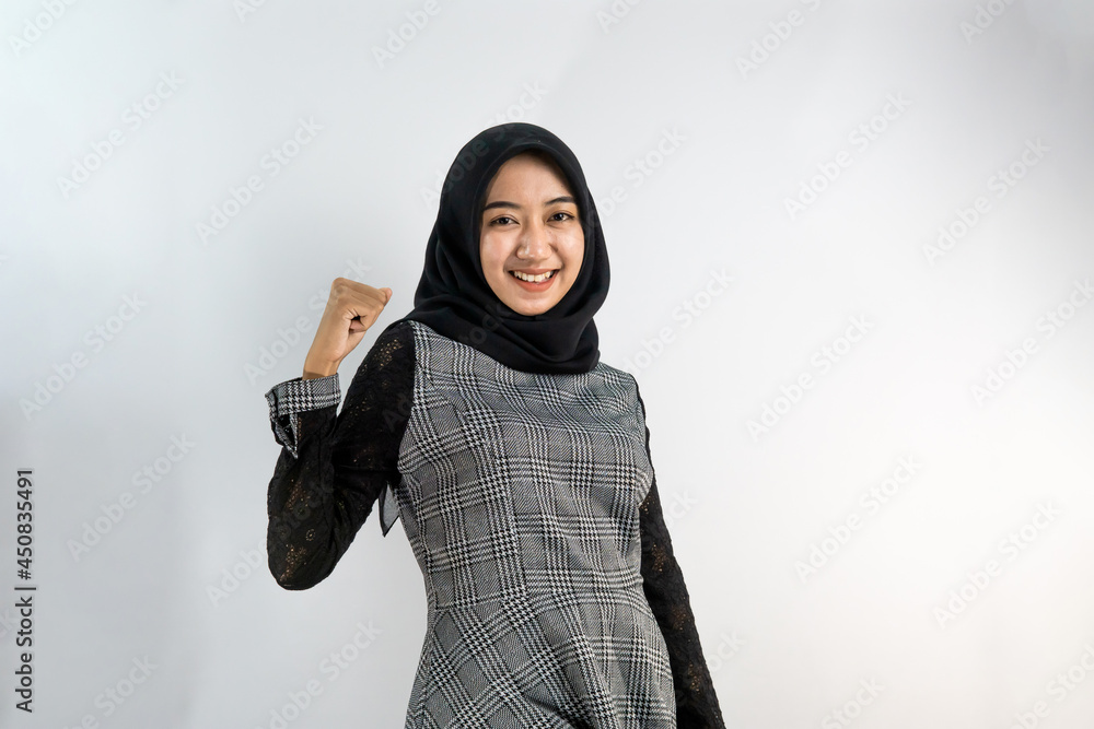 Beautiful young asian Muslim woman smiling confidently and excitedly with clenched fists, punching, ready to fight isolated on white background Beautiful young asian Muslim woman smiling confidently and excitedly with clenched fists, punching, ready to fight isolated on white background