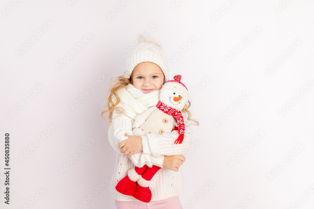 baby girl with snowman toy in warm hat and sweater on white isolated background, place for text