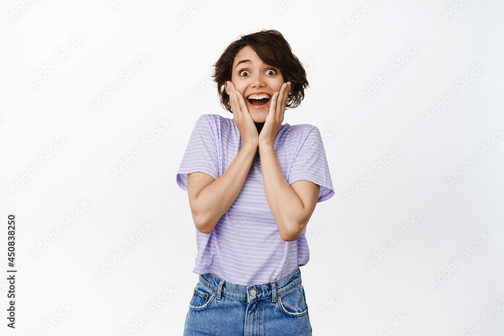 Surprised and excited brunette girl, smiling amazed, excited, receive awesome chance, fascinated with event, watching something great and impressive happening, white background Surprised and excited brunette girl, smiling amazed, excited, receive awesome chance, fascinated with event, watching something great and impressive happening, white background