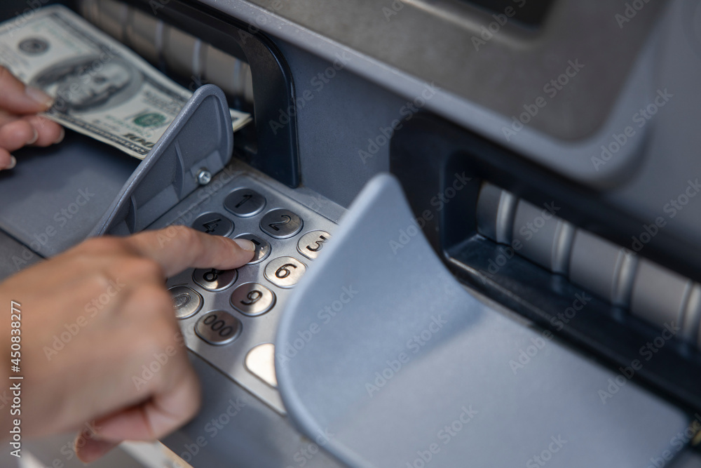 Female hand picking the cash from an ATM.