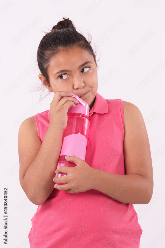 Portrait of a little girl drink from a plastic bottle through a straw while looking to the side Portrait of a little girl drink from a plastic bottle through a straw while looking to the side
