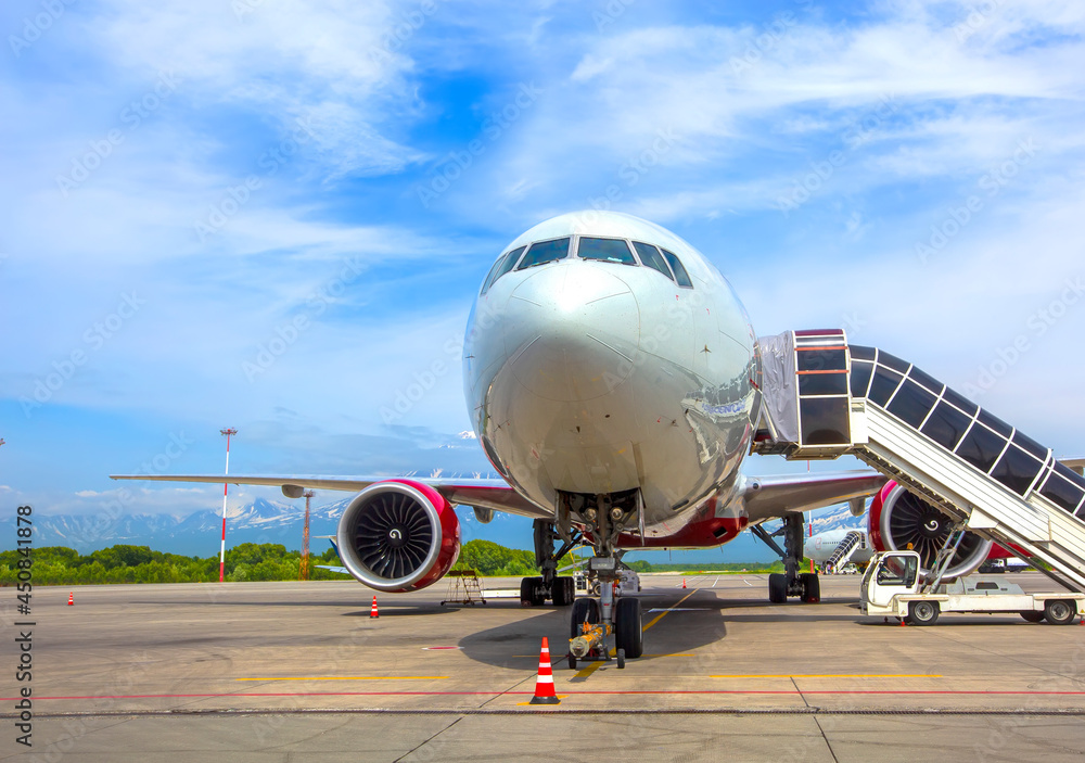 Airplane with a passenger boarding steps on the airport apron Airplane with a passenger boarding steps on the airport apron