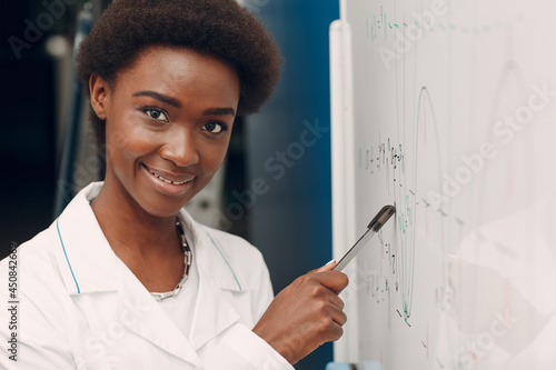 African American woman math univercity student writing on blackboard with marker close up