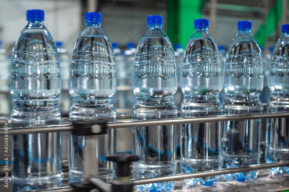 Plastic bottles with clean drinking water on the conveyor line in the production hall. Food production. Plastic bottles with clean drinking water on the conveyor line in the production hall. Food production.