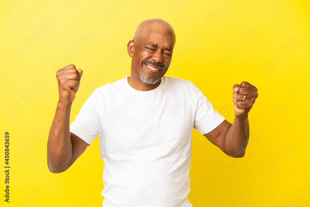 Cuban Senior isolated on yellow background doing strong gesture Cuban Senior isolated on yellow background doing strong gesture