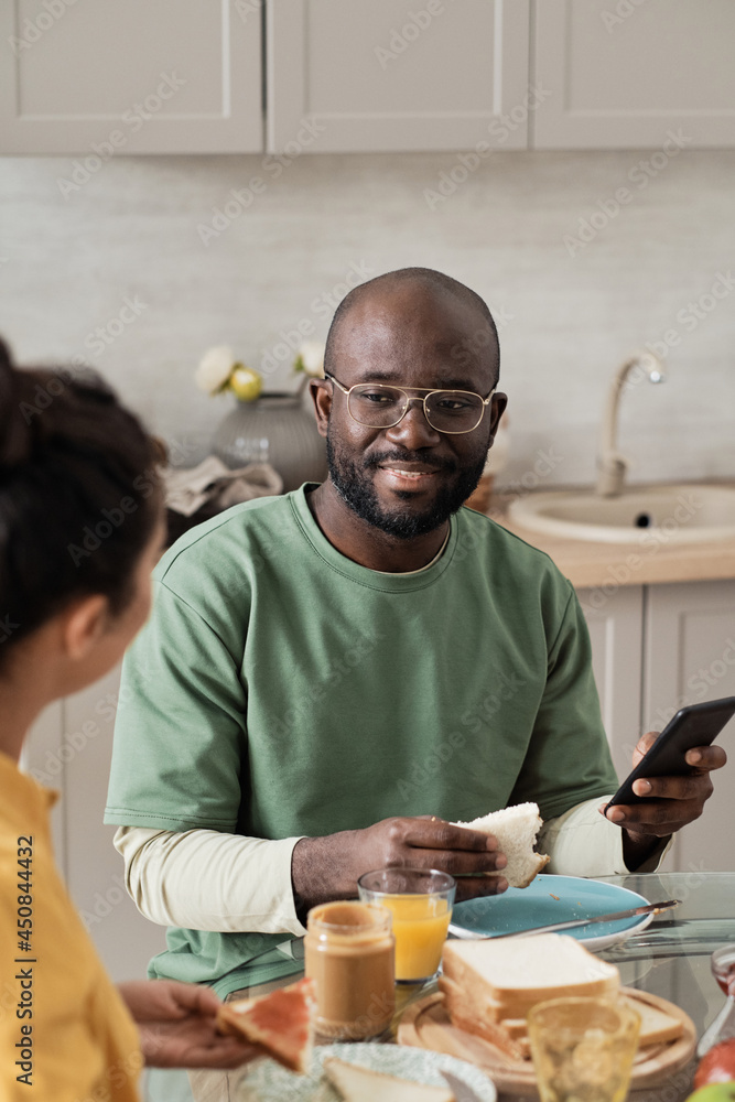 African young man talking to his wife while they sitting at the table and having breakfast African young man talking to his wife while they sitting at the table and having breakfast