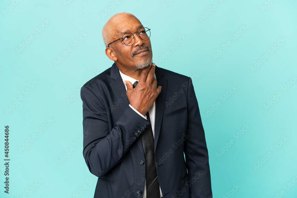 Business senior man isolated on blue background looking up while smiling Business senior man isolated on blue background looking up while smiling