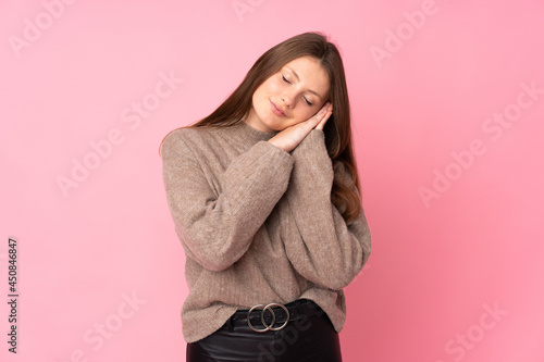 Teenager caucasian girl isolated on pink background making sleep gesture in dorable expression © luismolinero