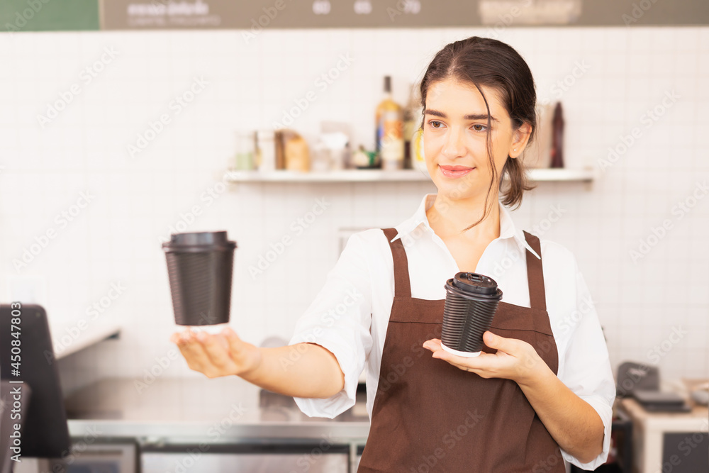 Beautiful caucasian barista woman show takeaway coffee cup in one hand and hold coffee cup in another hand at coffee bar Beautiful caucasian barista woman show takeaway coffee cup in one hand and hold coffee cup in another hand at coffee bar