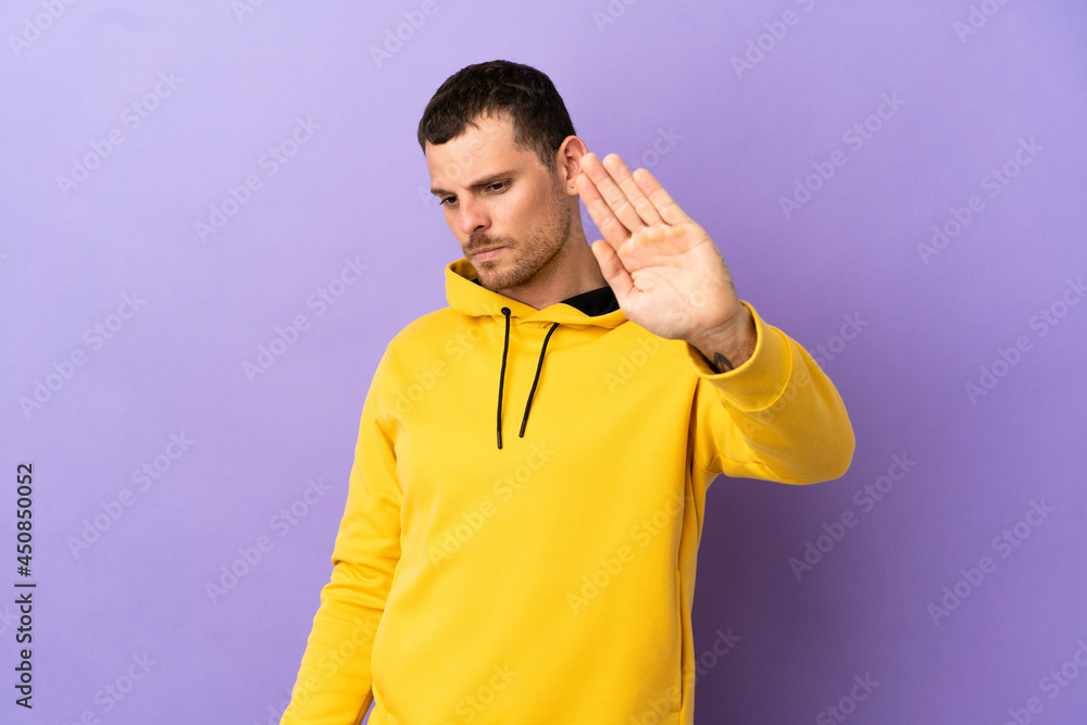 Brazilian man over isolated purple background making stop gesture and disappointed Brazilian man over isolated purple background making stop gesture and disappointed