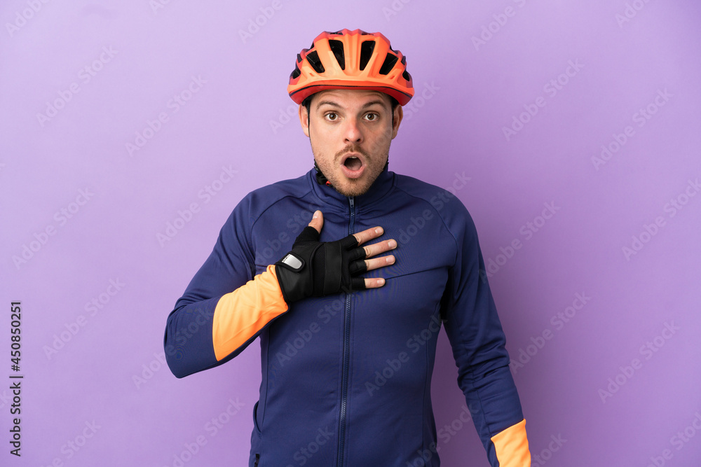 Young Brazilian cyclist man isolated on purple background surprised and shocked while looking right - obrazy, fototapety, plakaty 