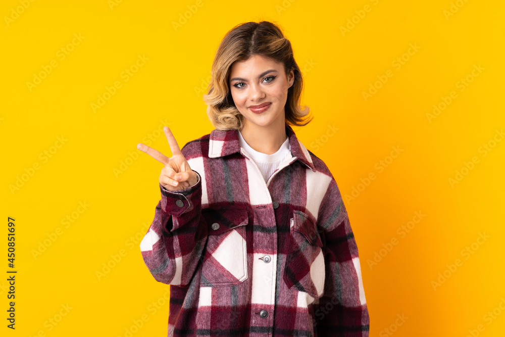 Young Russian woman isolated on yellow background smiling and showing victory sign Young Russian woman isolated on yellow background smiling and showing victory sign