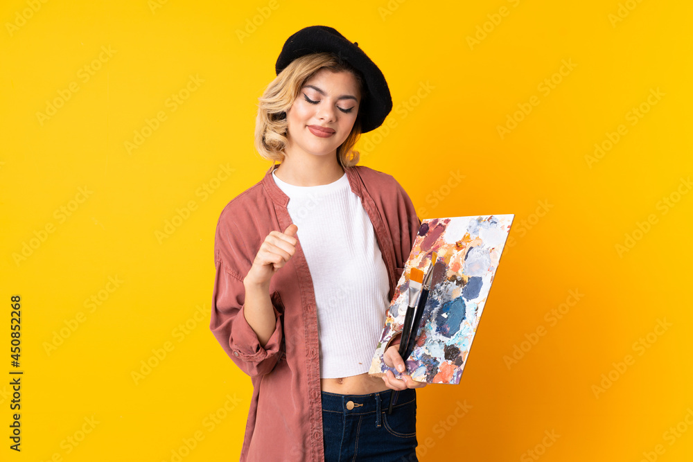 Young artist girl holding a palette isolated on yellow background proud and self-satisfied Young artist girl holding a palette isolated on yellow background proud and self-satisfied