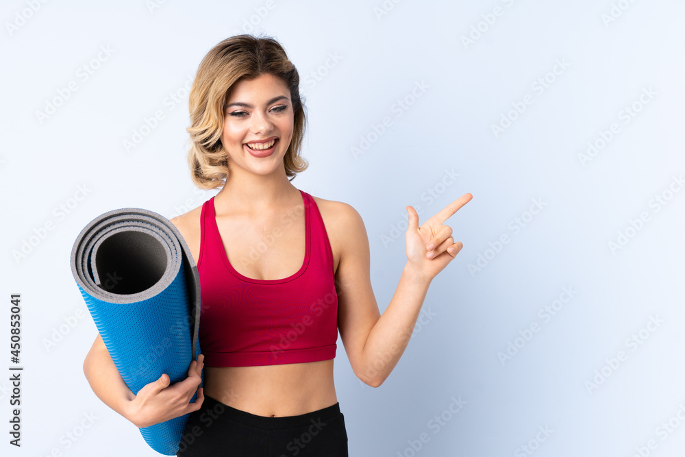 Russian girl with mat isolated on blue background surprised and pointing finger to the side Russian girl with mat isolated on blue background surprised and pointing finger to the side