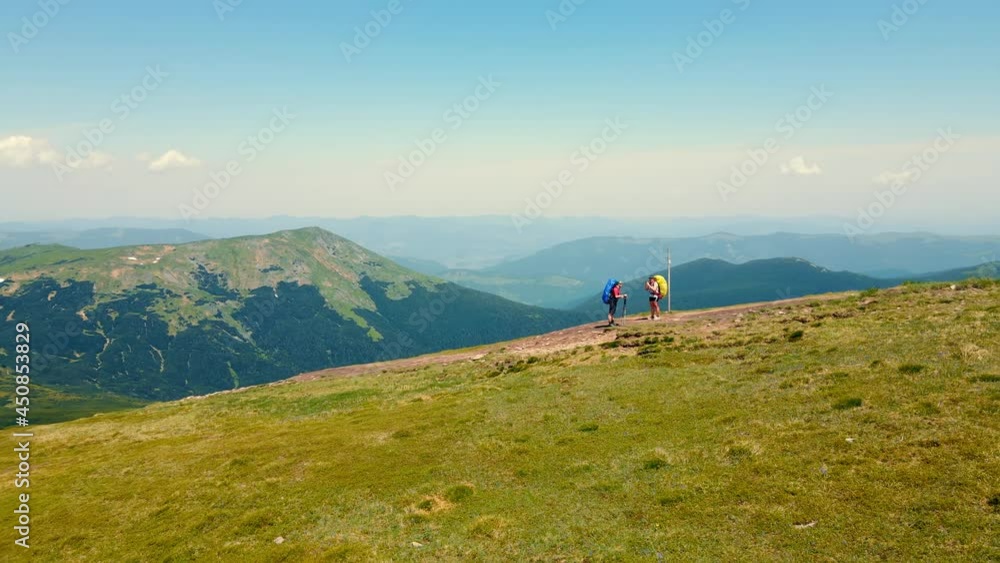 Two tourists are standing on the Montenegrin ridge. Aerial view tourists climbing to the top of the mountain on which the observatory and observation point are located. Journey to the top of the Two tourists are standing on the Montenegrin ridge. Aerial view tourists climbing to the top of the mountain on which the observatory and observation point are located. Journey to the top of the