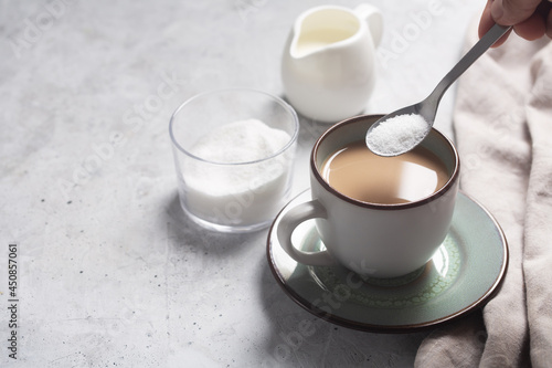 Spoon with sweetener over a cup of milk coffee photo