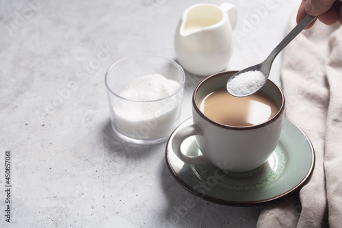 Photos Spoon with sweetener over a cup of milk coffee