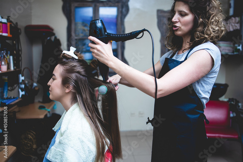 Side view of a woman customer getting a new hairstyle by female hairdresser.