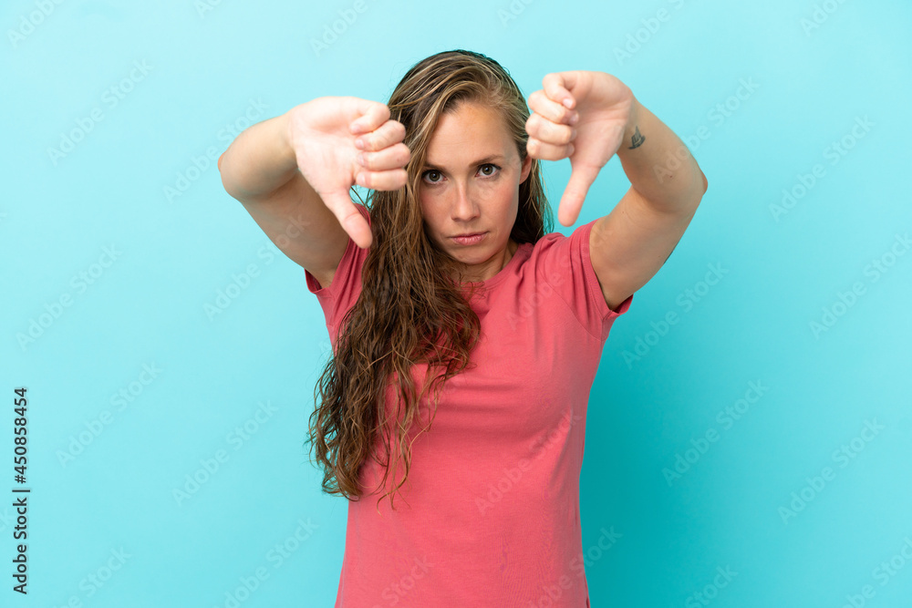Young caucasian woman isolated on blue background showing thumb down with two hands Young caucasian woman isolated on blue background showing thumb down with two hands