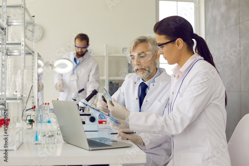 Group of male and female scientists and lab technicians doing advanced medical research  working on new vaccine and developing effective cure for diseases in modern science laboratory