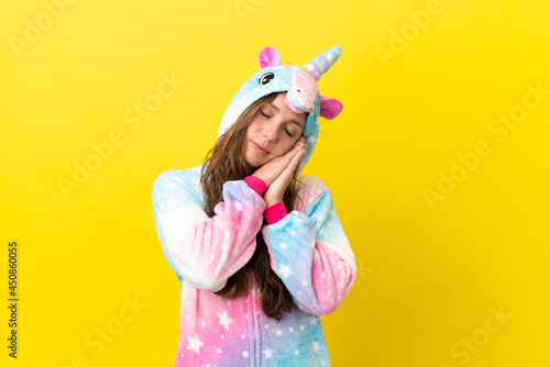 Girl with unicorn pajamas over isolated background making sleep gesture in dorable expression